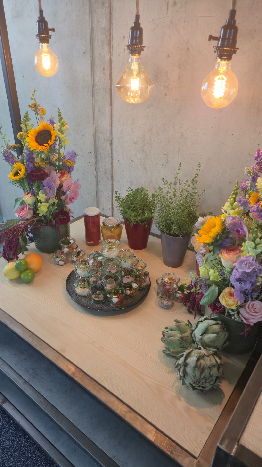 Finger food buffet with colourful glasses, fresh herbs and flowers on a wooden table in Lofthouse style