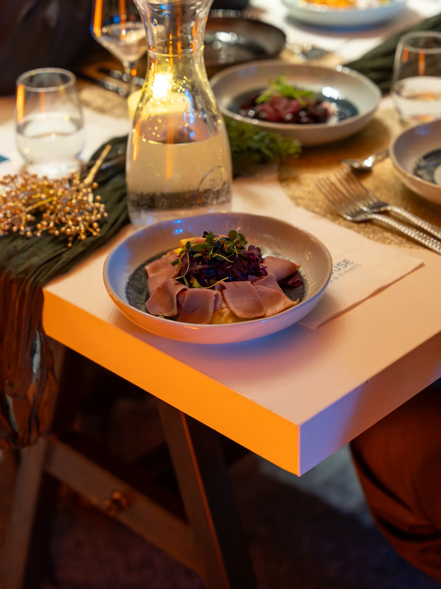 Geräucherte Entenbrust mit Rotkohlsalat in einer Schale auf einem festlich gedeckten Tisch
