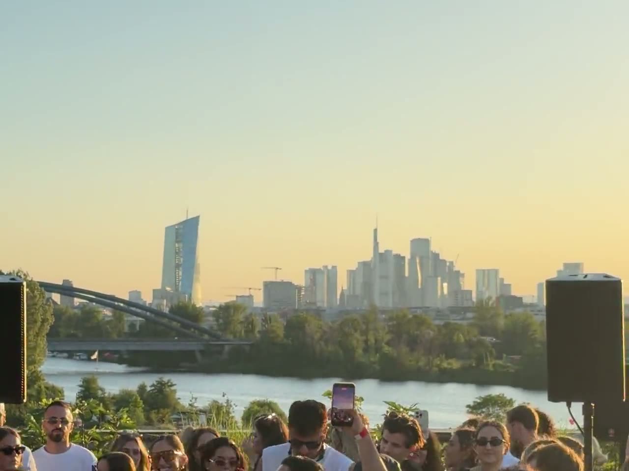 Feiernde Gäste bei Sonnenuntergang auf der Dachterrasse des Circle Cube mit Blick über den Main auf die Frankfurter Skyline